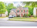 Two-story brick home with red accents, lush landscaping, and a two-car garage at 5008 Bethpage Dr, Suwanee, GA 30024