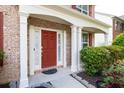 Inviting brick home entrance featuring a red door and decorative white pillars at 5008 Bethpage Dr, Suwanee, GA 30024