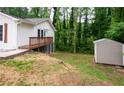 Backyard with a deck, storage shed, and lush green trees in the background at 1563 Brannon Sw Cir, Austell, GA 30106