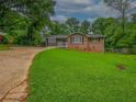 Quaint single-story home with brick and gray siding, a well-maintained lawn, and mature trees at 6892 Autumn Hills Dr, Douglasville, GA 30135