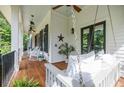 Spacious covered porch featuring hanging swing, ceiling fans, wood floors, and white columns at 132 Mount Vernon Dr, Decatur, GA 30030