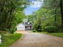 Secluded two-story home with white siding and black shutters nestled among lush green trees at 1620 Bluewater Ct, Cumming, GA 30041