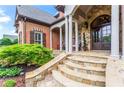 Elegant stone steps leading to a covered porch with stone pillars and a detailed front door with beautiful landscaping at 31 Brownson Ct, Acworth, GA 30101