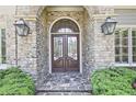 Elegant front door with stone surround, decorative glass, and flanking sconces at 5118 Greythorne Ln, Marietta, GA 30068