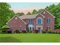 Beautiful two-story brick home with a large front yard and mature trees at sunset at 4734 Eagles Ridge Loop, Lithonia, GA 30038