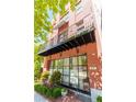 Close up of a multi-story brick townhome with a small balcony, large windows, and landscaping at 89 E Andrews Nw Dr, Atlanta, GA 30305