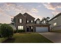 Beautiful two-story brick home featuring a well-manicured lawn and a two-car garage at dusk at 1612 Nations Trl, Riverdale, GA 30296