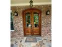 Elegant double front door with glass panels, set within a brick archway and stone tile porch at 3397 Holly Glen Dr, Dacula, GA 30019