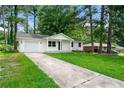 Inviting white brick home with an attached garage and a long driveway, complemented by a green lawn at 1660 Mallard Cir, Conley, GA 30288