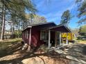 Low angle of a red house showing the front porch and a yard covered in leaves at 6475 Church St, Atlanta, GA 30291