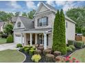 Well-maintained exterior with manicured landscaping, green lawn, and a charming covered porch area at 2376 Roberts View Trail, Buford, GA 30519