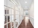 Elegant hallway features dark hardwood floors, white wainscoting, and glass french doors at 5195 Belmore Manor Ct, Suwanee, GA 30024