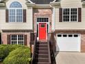 Inviting home with brick accents, a striking red front door, and an attached two-car garage at 136 Walkers Pond Dr, Villa Rica, GA 30180