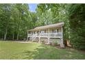 Cozy house with a welcoming front porch and lush green lawn surrounded by mature trees at 92 Confidence Ct, Temple, GA 30179