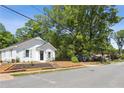 View of the charming white house with neat landscaping, set against a backdrop of mature trees and a quiet street at 130 South Se Ave, Marietta, GA 30060