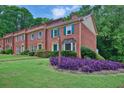 Classic brick townhouse with green lawn, vibrant landscaping, and inviting curb appeal at 6139 Keswick Row, Tucker, GA 30084