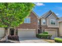 Two-story townhome showcasing brick and shingle facade, with attached garage and neat landscaping at 2167 Crestridge Ne Trl, Brookhaven, GA 30329