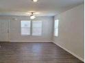 A bright, open living room with three large windows and sleek hardwood floors provides modern comfort at 115 Deer Xing, Temple, GA 30179