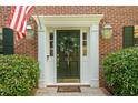 Close-up of a front door with a wreath, sidelights, an American flag, and lanterns at 815 Lake Forest Pass, Roswell, GA 30076