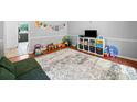 A playroom with wood floors, a white rug, and decorated with toys, books, and wall art at 815 Lake Forest Pass, Roswell, GA 30076