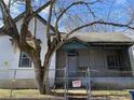 View of the front exterior, which includes a chain link fence, tree, and small front porch at 701 Garibaldi St, Atlanta, GA 30310