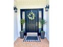 Elegant black front door with a decorative wreath, flanked by potted plants and stylish lanterns at 805 Doe Hill Ln, Roswell, GA 30075