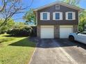 Split-level home featuring a two-car garage, brick accents, and a driveway with parking at 4457 Huntshire Dr, Stone Mountain, GA 30083