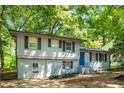 Split-level home featuring black shutters, painted brick, landscaped yard, and blue door at 271 Leafwood Ln, Riverdale, GA 30274