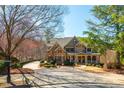 A charming home boasts a stone and brick exterior, surrounded by a well-manicured lawn and mature trees at 930 Shepards Ct, Roswell, GA 30075
