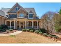 Inviting home featuring a covered front porch with stone and brick, complemented by a lush, landscaped yard at 930 Shepards Ct, Roswell, GA 30075