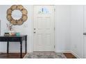Inviting entryway featuring a white door with glass detail, dark wood floors, and a decorative mirror at 1560 Avalon Creek Rd, Sugar Hill, GA 30518