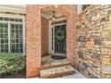 Inviting front entrance featuring brick and stone accents, a wreath-adorned door, and a charming pendant light at 5303 Davenport Mnr, Cumming, GA 30041