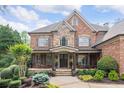 Charming brick and stone home showcasing meticulous landscaping and inviting front porch at 5475 Copper Creek Pass, Cumming, GA 30040
