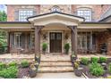 Inviting front porch with stone columns, double doors, and elegant landscaping at 5475 Copper Creek Pass, Cumming, GA 30040