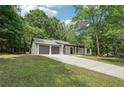 View of the house with a two-car garage and a well-maintained lawn surrounded by lush trees at 250 Huntcliff Ct, Fayetteville, GA 30214