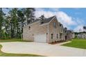 Side view of a brick home featuring an attached two-car garage and a well-maintained lawn at 322 Delta Dr, Mcdonough, GA 30253