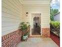 Inviting front porch with brick accents, a stylish light fixture, and a view into the living area at 6071 Apple Grove Rd, Buford, GA 30519