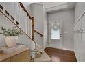 Entryway with staircase featuring hardwood floors, a wooden handrail, and white wainscoting at 5437 Blossom Brook Dr, Sugar Hill, GA 30518