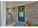 Inviting entryway with a brick facade, a wreath-adorned door, and stylish checkered outdoor rug at 5437 Blossom Brook Dr, Sugar Hill, GA 30518