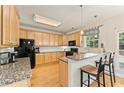 Well-lit kitchen featuring granite countertops, stainless steel appliances, breakfast bar with pendant lights, and hardwood floors at 525 Roland Manor Dr, Dacula, GA 30019