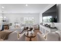 Bright living room with a large white sectional sofa, hardwood floors, and a wall-mounted TV at 1388 Ben Park Way, Grayson, GA 30017