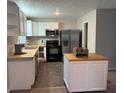 Well-lit kitchen featuring stainless steel appliances, white cabinets, and a butcher block island at 3990 N Quail Dr, Douglasville, GA 30135