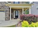 Inviting front porch with stone accents, colorful flower beds, and a charming entrance at 6468 Pierless Ave, Sugar Hill, GA 30518