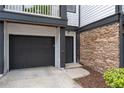 A close-up of a townhouse showcasing stone accents, a black garage door, and a covered entrance at 220 Semel Cir # 150, Atlanta, GA 30309