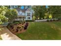 Two-story home with manicured lawn, colorful landscaping, and a charming white picket fence bordering the property at 4853 Ridgewood Creek Nw Dr, Acworth, GA 30102