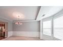 Elegant dining room with a tray ceiling, large windows, decorative wainscoting, and a chandelier at 7979 Larksview Dr, Fairburn, GA 30213