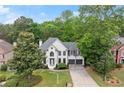 Wide angle view of a white brick two-story home with gray trim, a well manicured lawn and mature trees at 4294 Silver Peak Pkwy, Suwanee, GA 30024