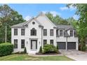 Elegant white brick home with dark trim, a manicured lawn, and a three-car garage at 4294 Silver Peak Pkwy, Suwanee, GA 30024