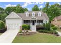Charming home with a welcoming front porch, beautiful landscaping, and a large driveway leading to the garage at 2084 Democracy Dr, Buford, GA 30519