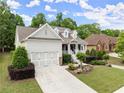 Charming home with a welcoming front porch, beautiful landscaping, and a large driveway leading to the garage at 2084 Democracy Dr, Buford, GA 30519